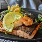 Mediterranean table with olive oil, bread, vegetables, and grilled fish